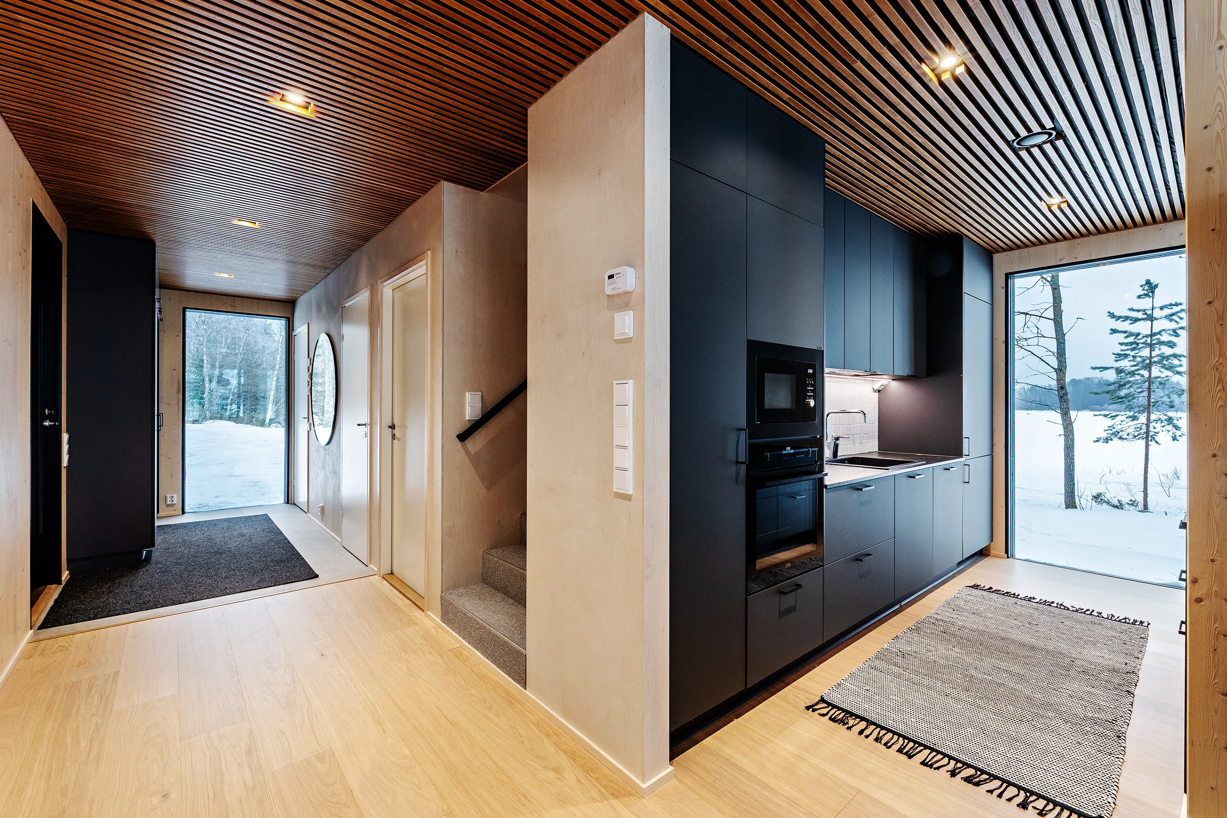 Villa Lehtoniemi moderni huvila, jossa tumma keittiö ja avarat ikkunat